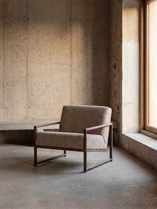 Armchair Einar in greige bouclé on a dark stained oak frame in a minimalist concrete interior