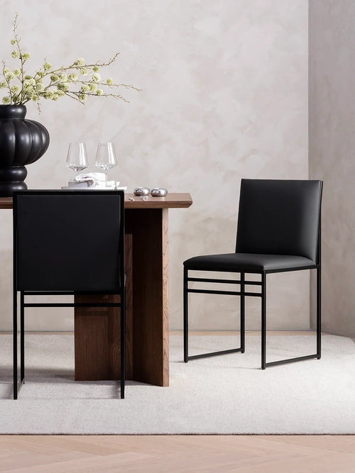 Dining chair Isabell with black leather cushion and black frame in modern dining setting.