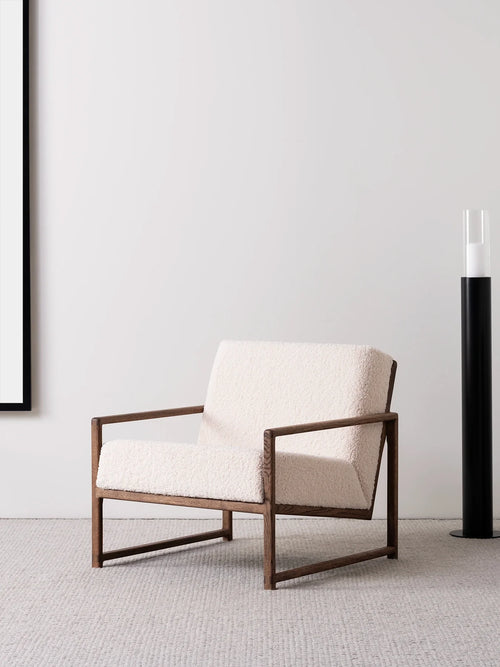 Armchair Einar featuring dark oak frame and ivory bouclé cushion, perfect for Scandinavian-style living spaces.